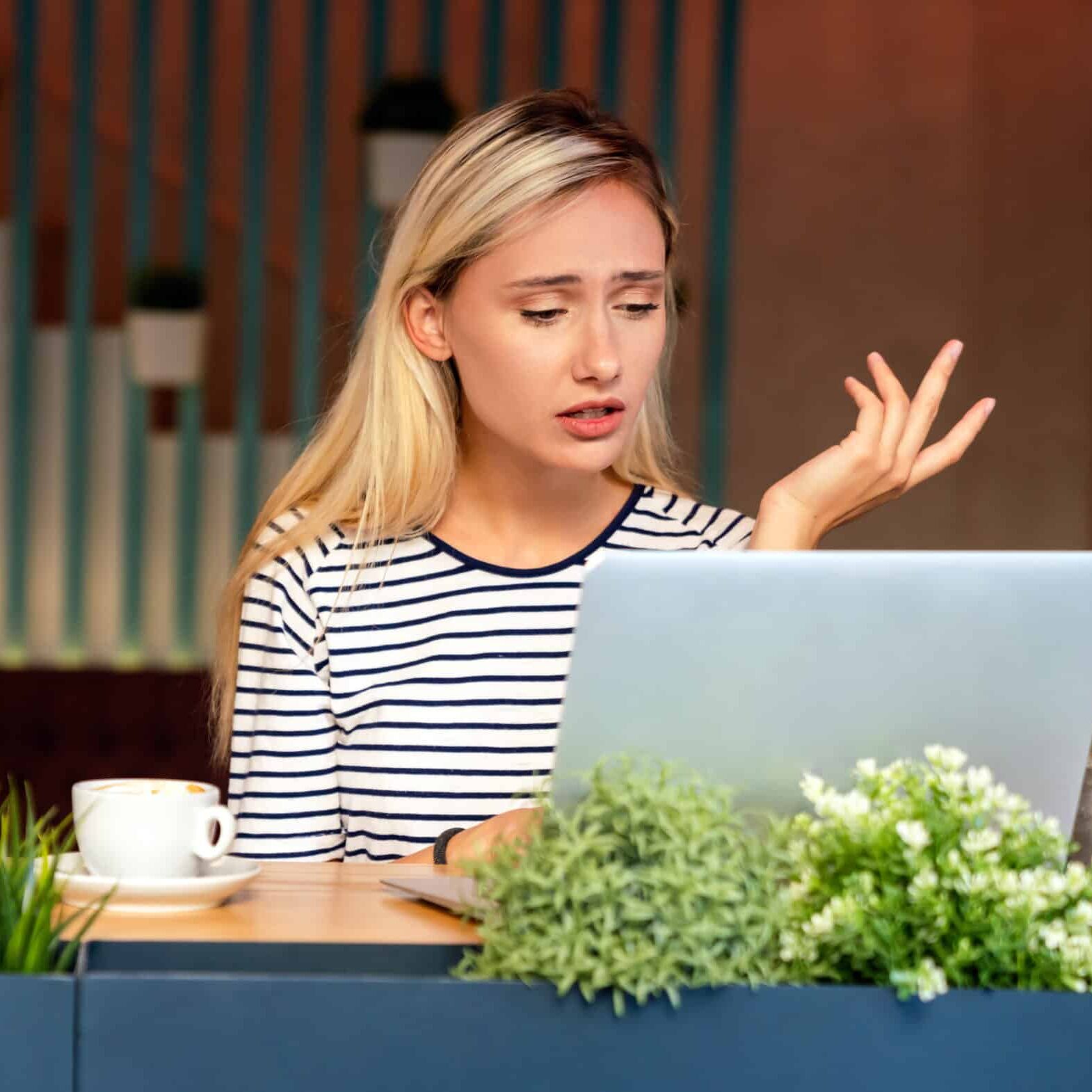 Blonde Frau sitzt erklärend vor einem Laptop und führt ein Online Meeting